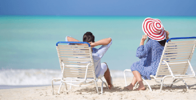 Rückenansicht einer Frau und eines Mannes auf Liegestühlen am Strand. 