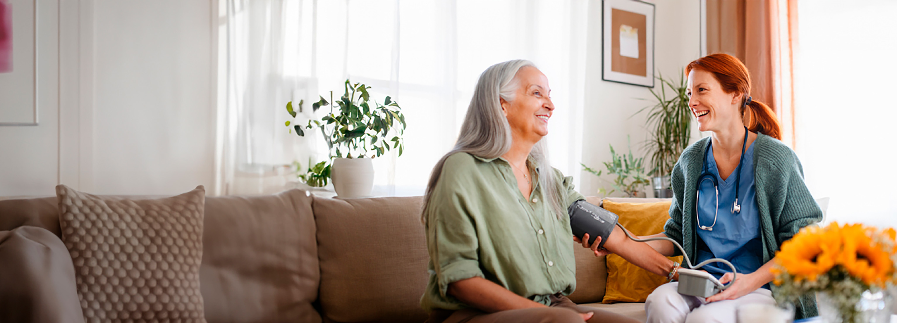 Pflegerin misst Blutdruck bei Seniorin