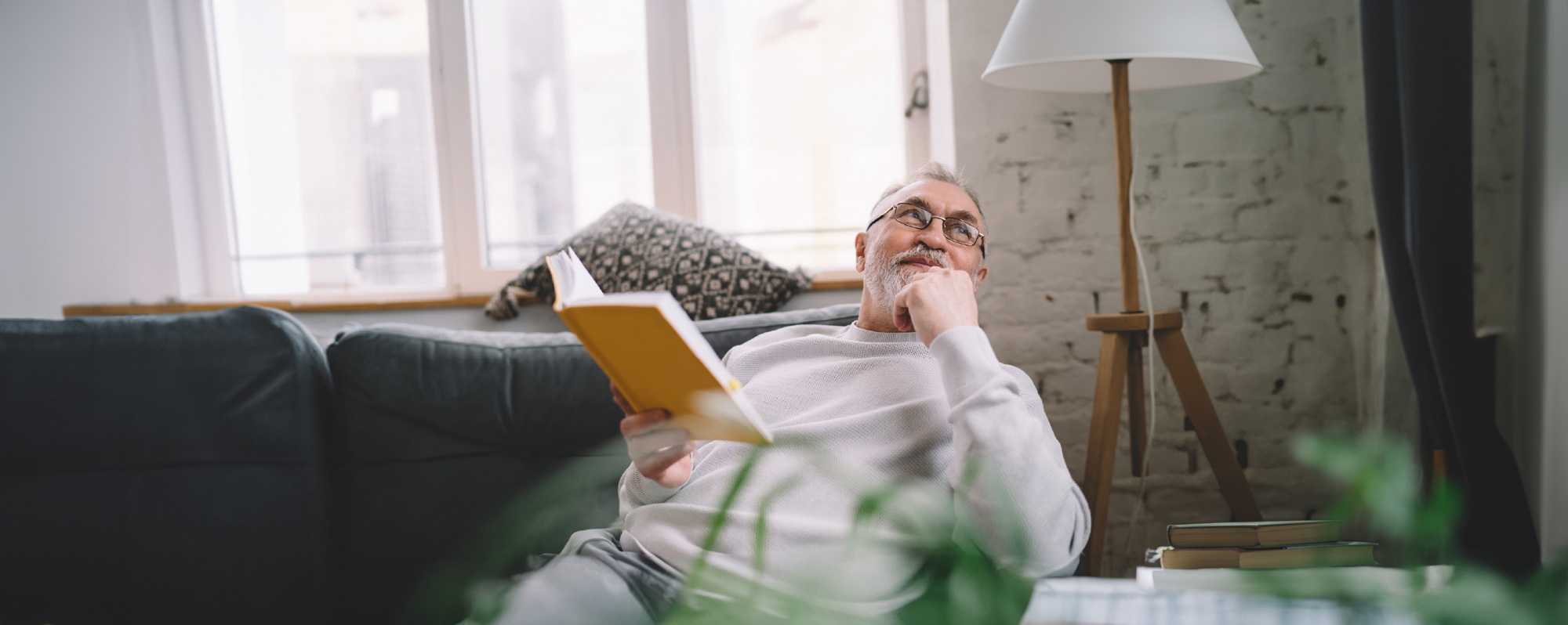 Mann sitzt auf Couch und liest ein Buch